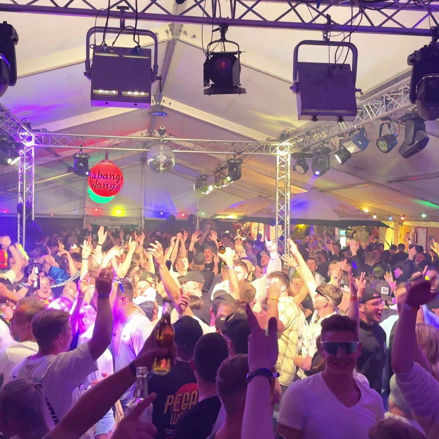 Volles Festzelt bei einer Party mit DJ@Knight: G&auml;ste feiern mit erhobenen Armen unter Moving Heads und Discokugel