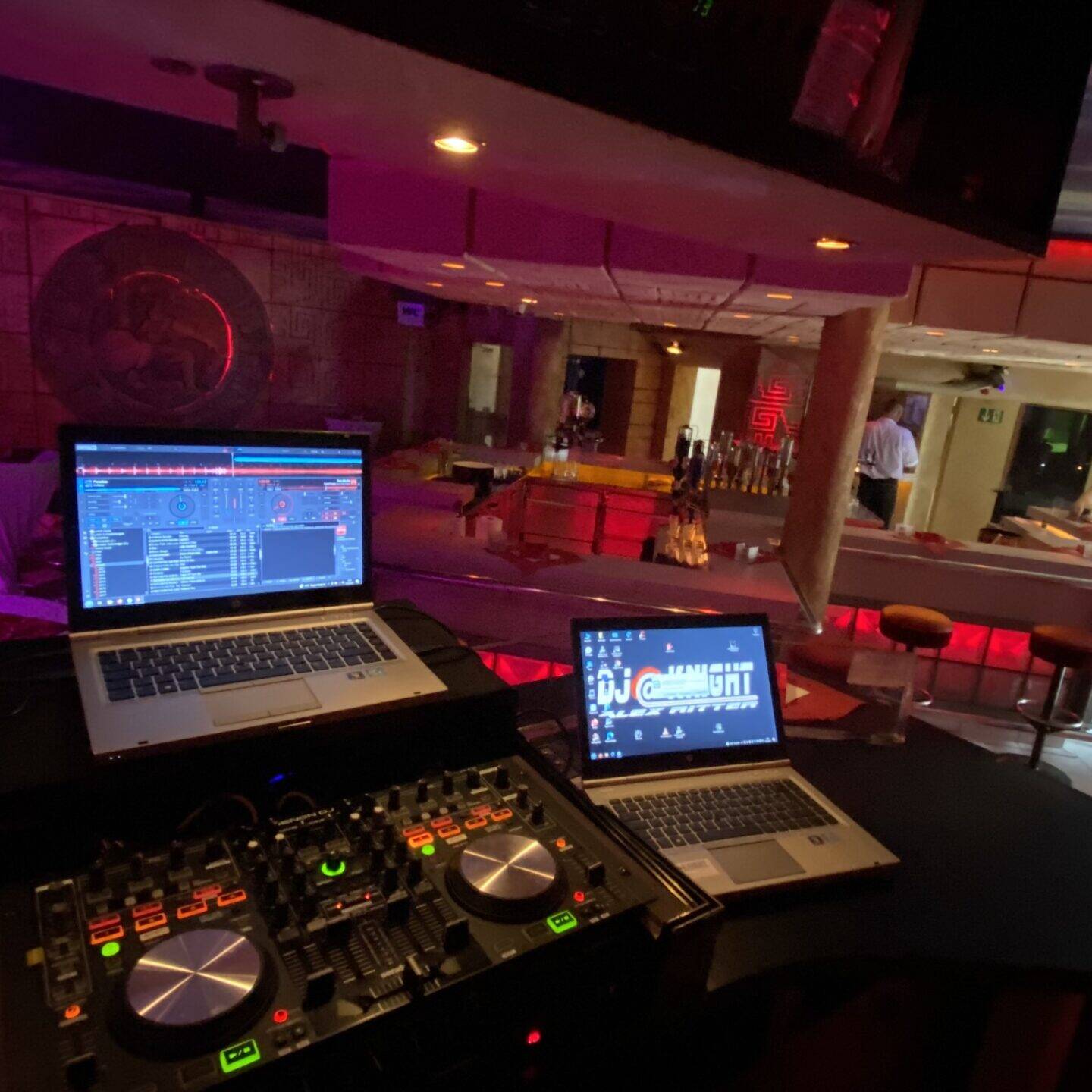 DJ-Pult mit Controller und zwei Notebooks in einer Bar, auf einem Bildschirm das DJ@Knight-Logo